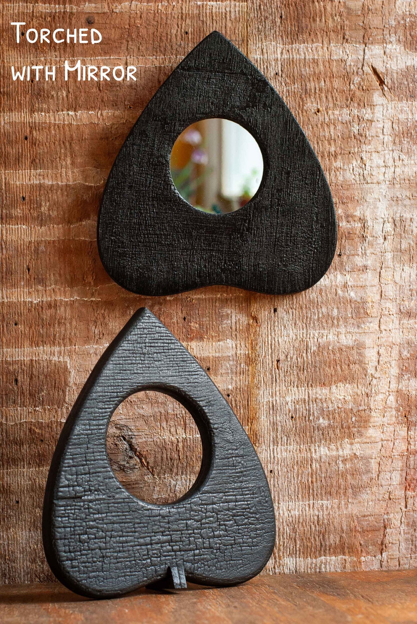 Two teardrop-shaped Ouija Planchette mirrors with a 'Torched' effect on a wooden surface.