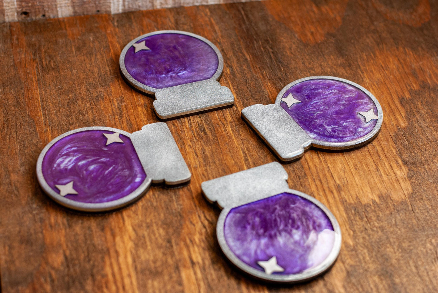 A set of four purple and silver mystical celestial-themed resin crystal ball coasters with a star on a wooden tabletop