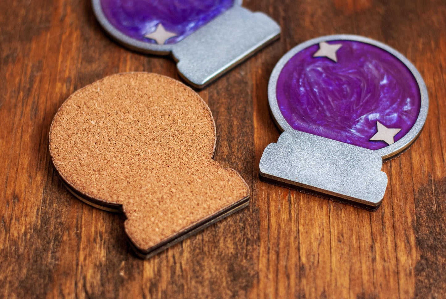 Decorative drink coasters with cork base and purple crystal ball design on a wooden surface