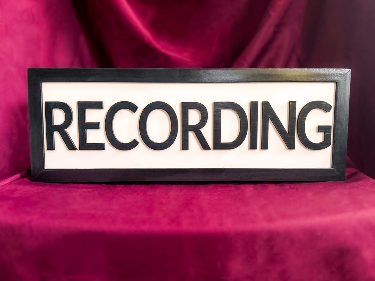 black recording studio light sign and on a table with red tablecloth and drape