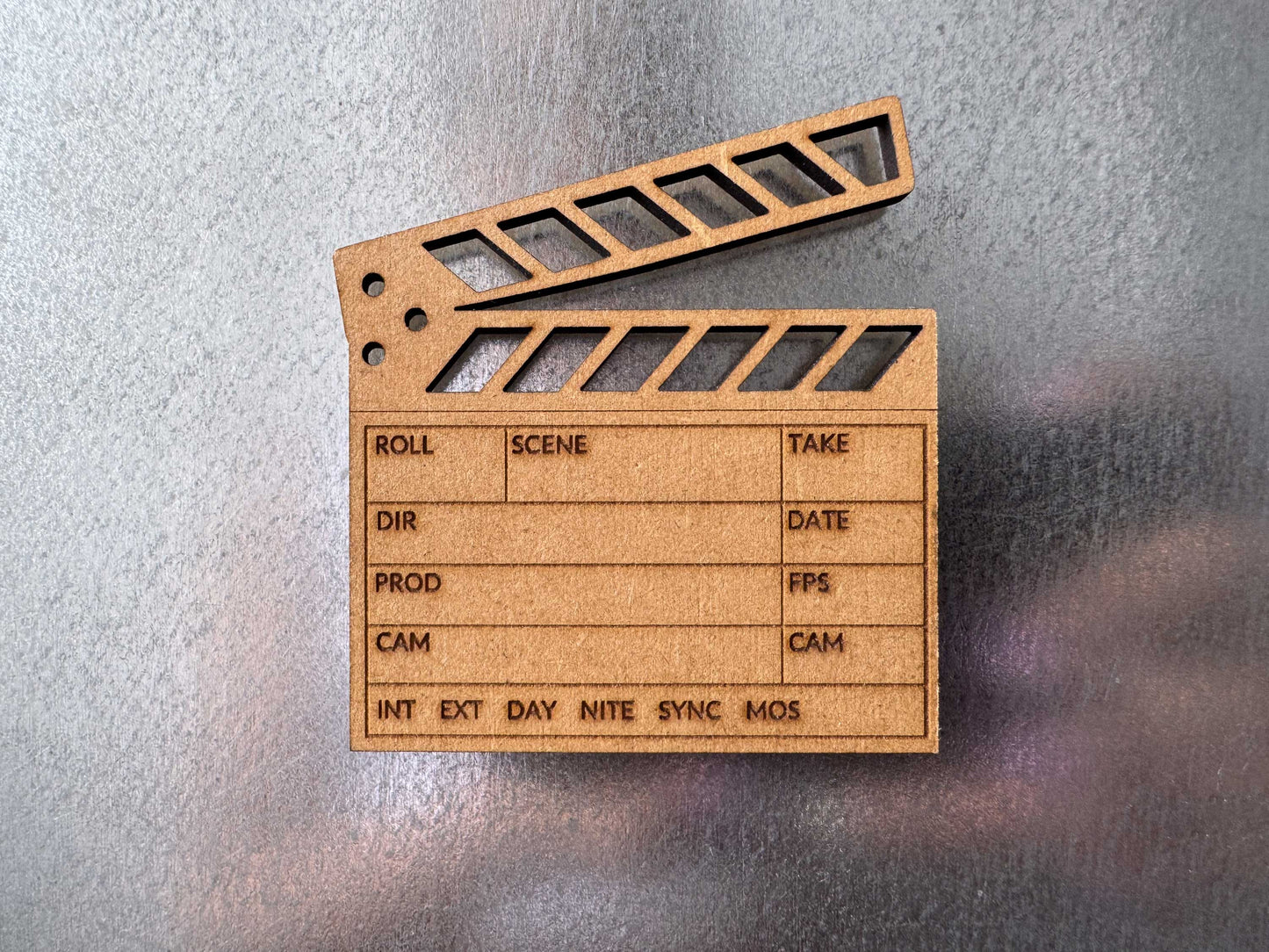 close up view of a brown engraved wood clapboard magnet on a metal fridge