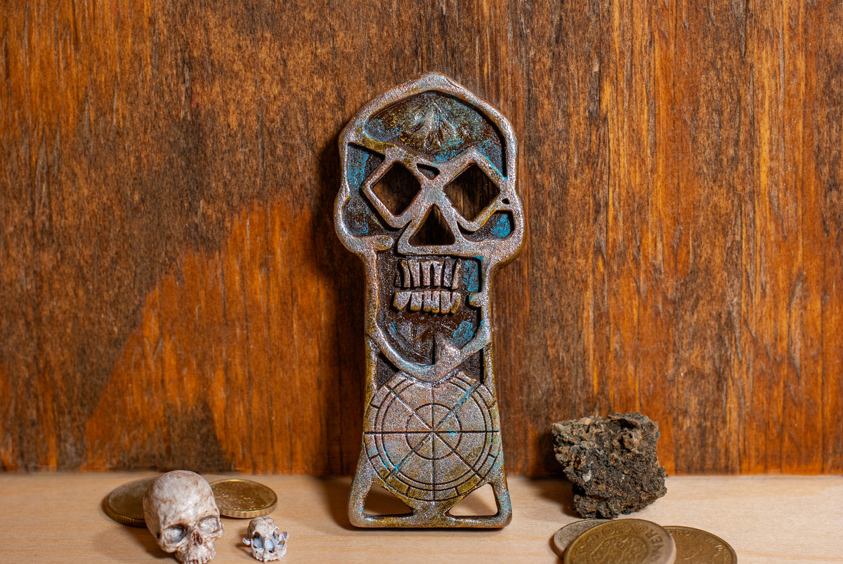 A copper bones skeleton key with bones and gold coins near by with a wooden background