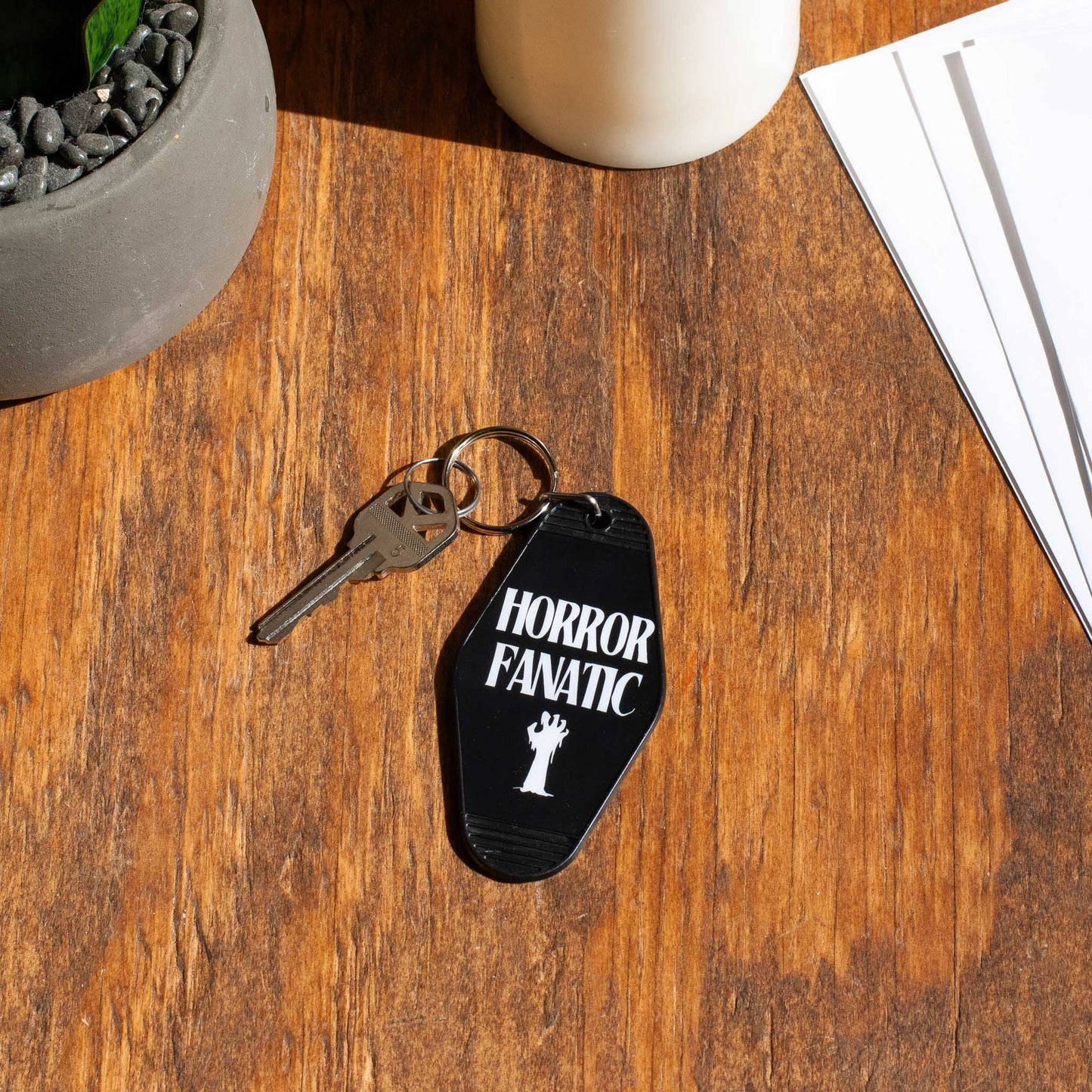 top view of a motel keychain with 'Horror Fanatic' text on a wooden surface