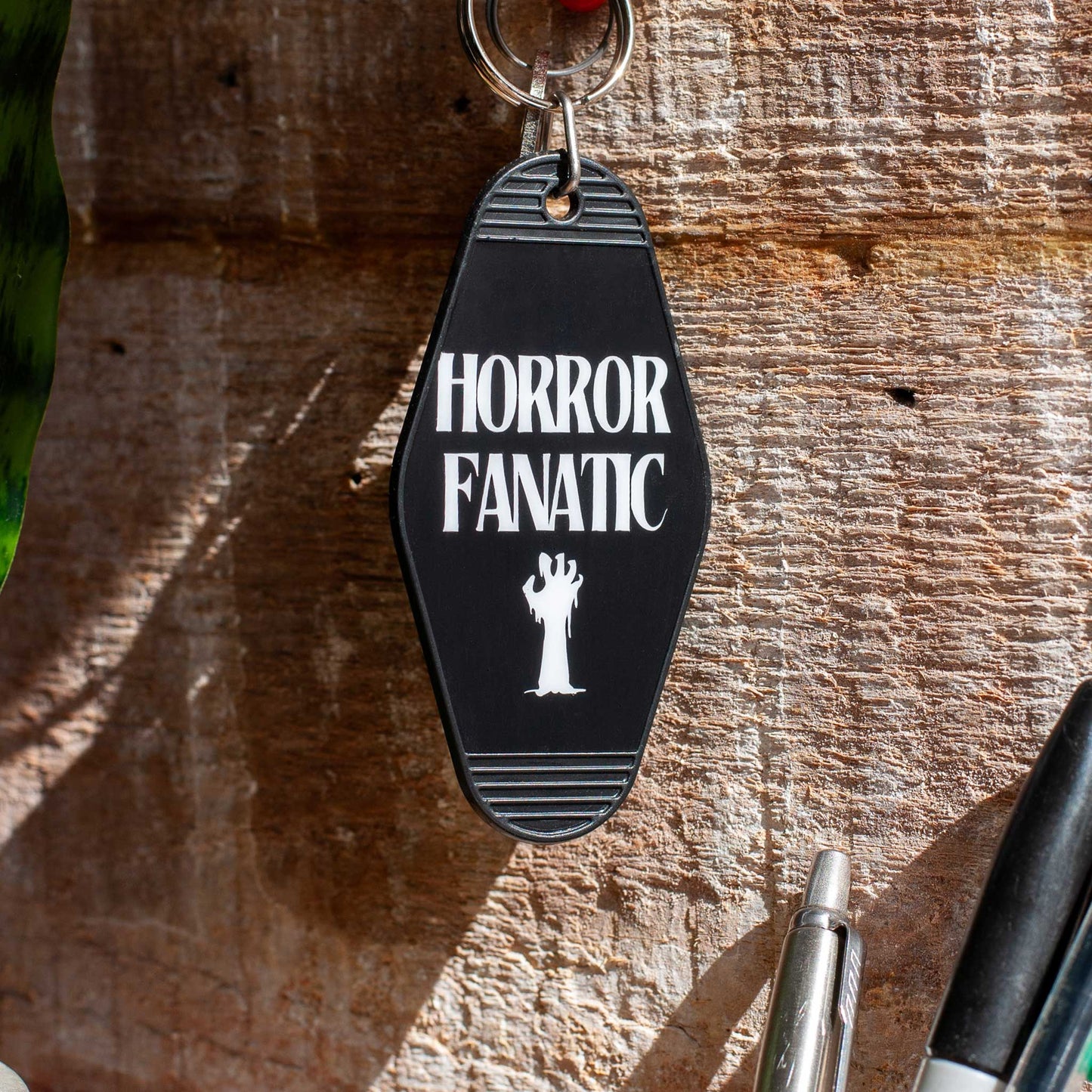 close up view of black horror fanatic motel keychain, motel keychain for horror fans, horror tag for key