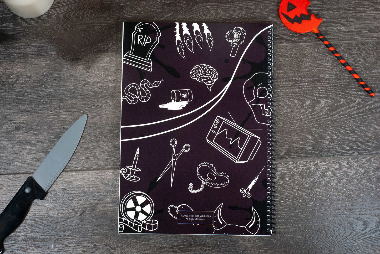 back cover of the Horror Movies Recap Book a horror movie review journal on a wooden table with halloween decorations