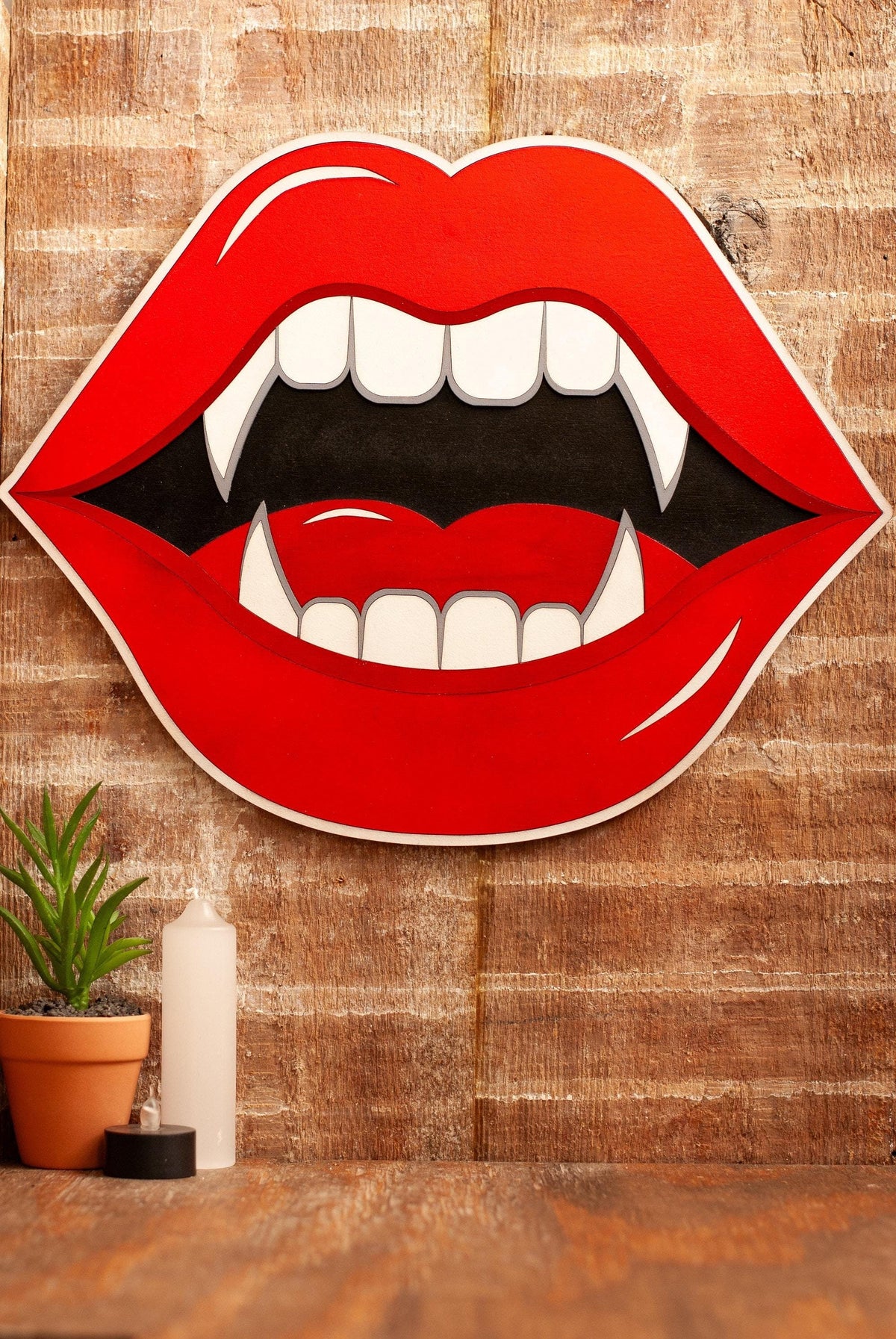 Decorative wall art of red lips with fangs on a wooden background