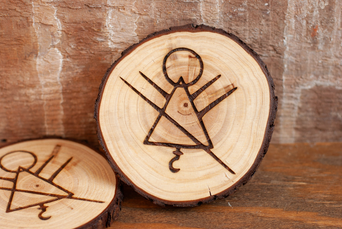 Wooden coasters with engraved stick figure rune symbol on a wooden background
