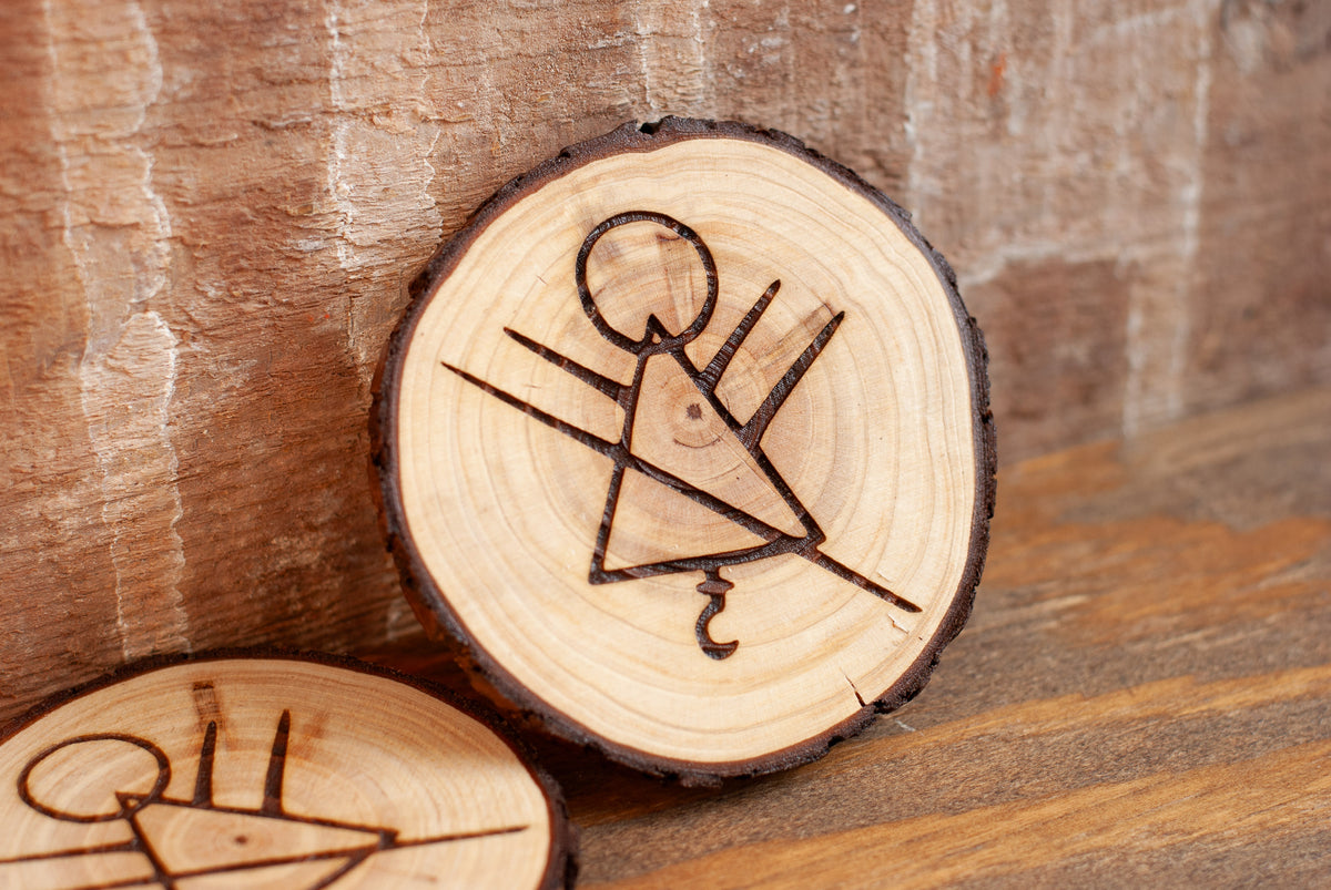 Wooden coaster with engraved stick figure rune symbol on a wooden surface