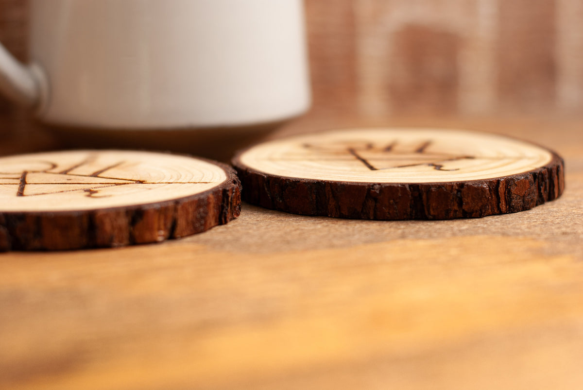 Side view of wooden coasters with laser-engraved rune symbol designs on a wooden surface.