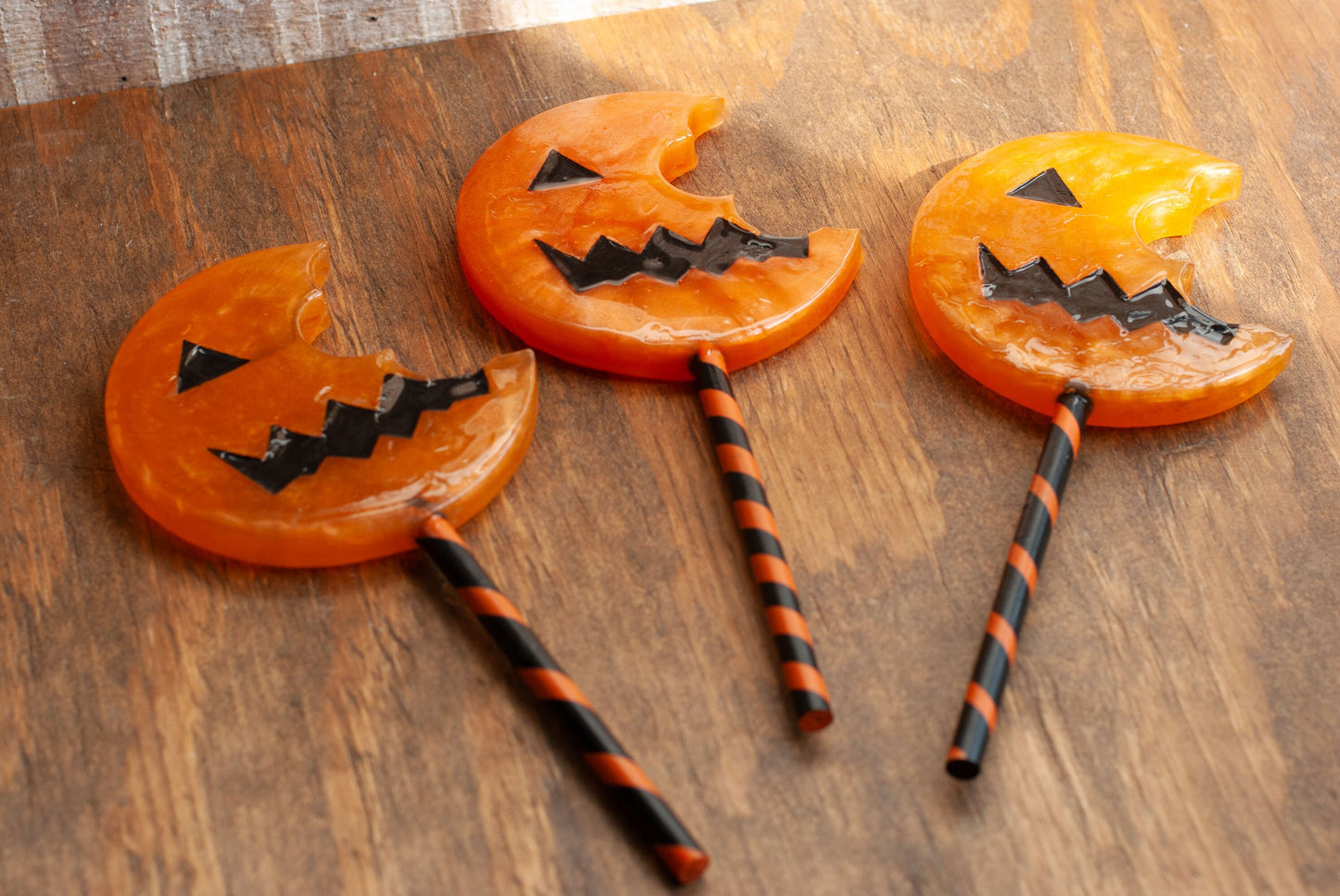 Three black and orange Halloween-themed horror movie pumpkin lollipop props made of resin for trick or treat and cosplay displayed on wooden table