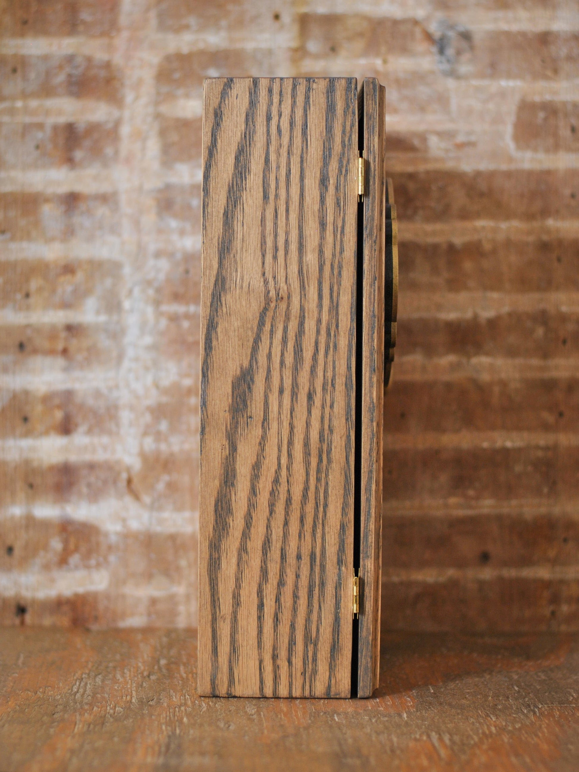 Side view of a rustic wooden apothecary box against a brick background and wooden tabletop.