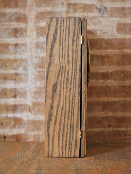 Side view of a rustic wooden apothecary box against a brick background and wooden tabletop.