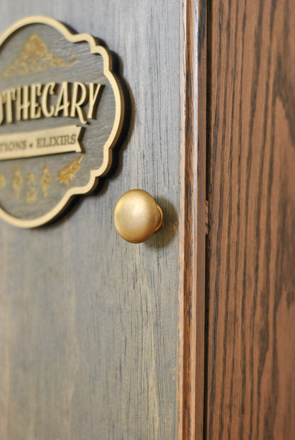 Close-up of a rustic apothecary box with bronze gold knob and sign that reads "Apothecary Potions Elixirs".