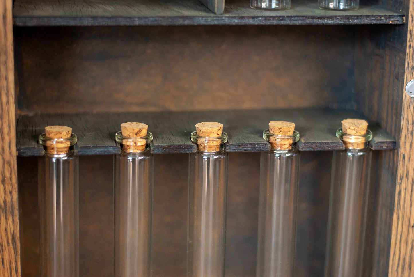 close-up view of a set of test tubes with cork stoppers hanging on a rustic wooden shelf in an apothecary box