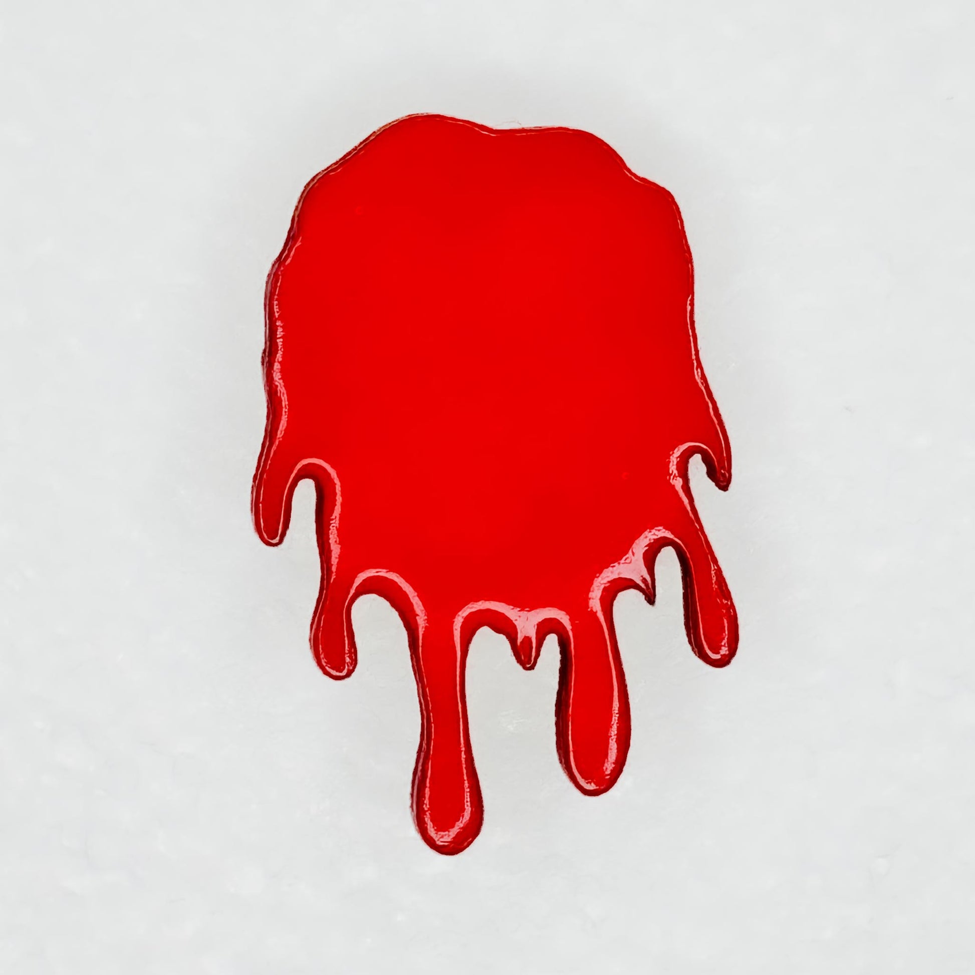 Close up view of red blood dripping designed pin for backpack, shirt, or bag on a white background
