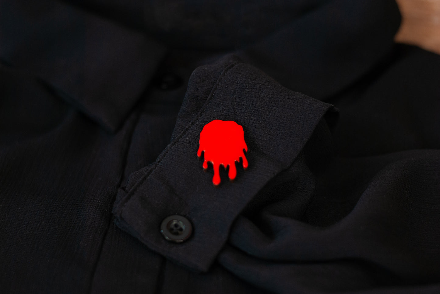 Red blood drop pinback style button on a black shirt