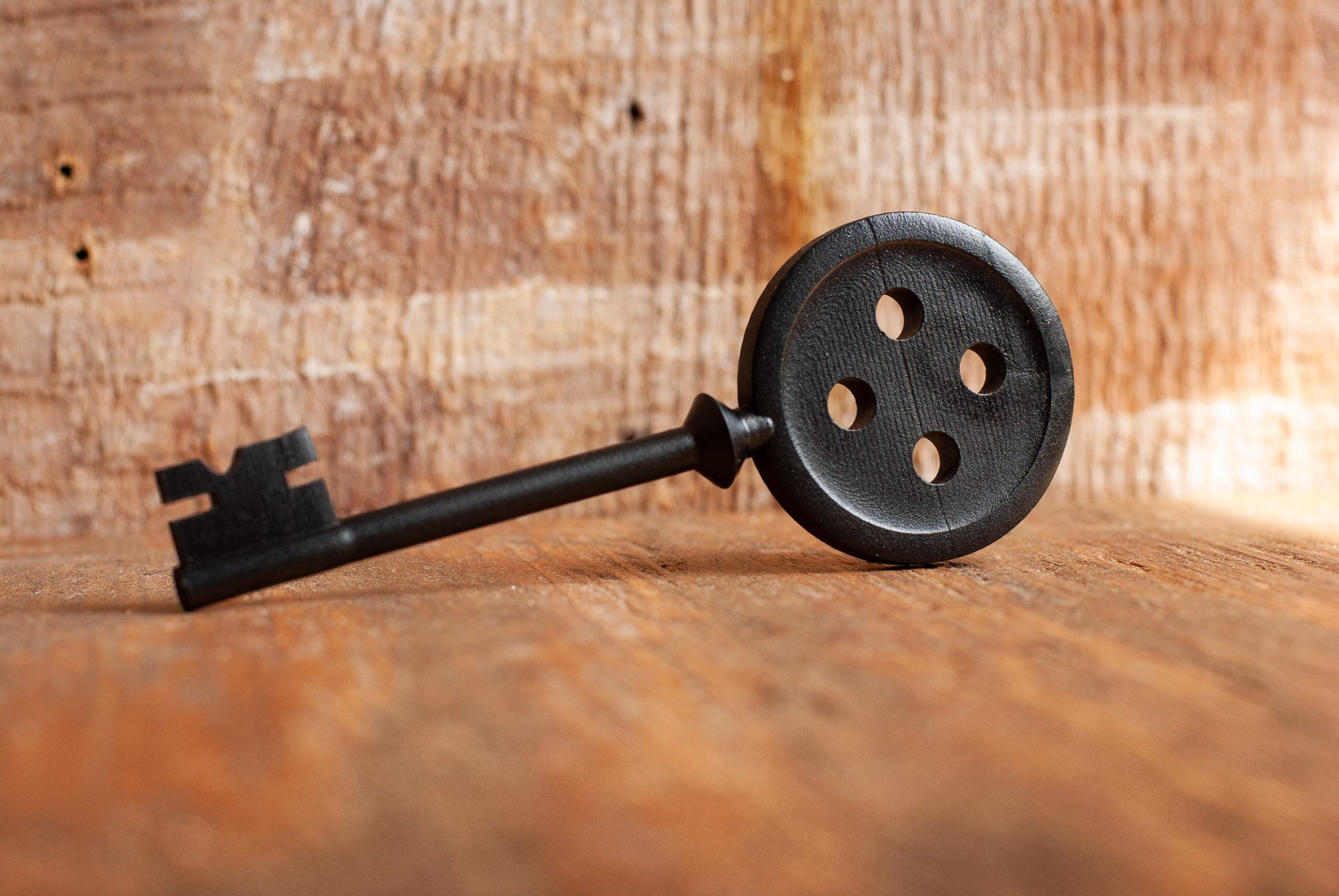 Black Coraline inspired button key prop replica on wooden table