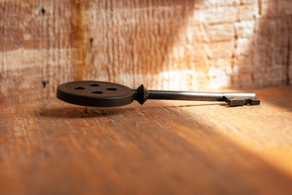 Black Coraline inspired button key prop replica laying on wooden table