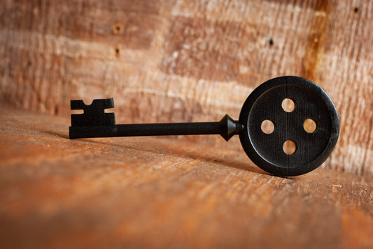 Black Coraline inspired button key prop replica on wooden table