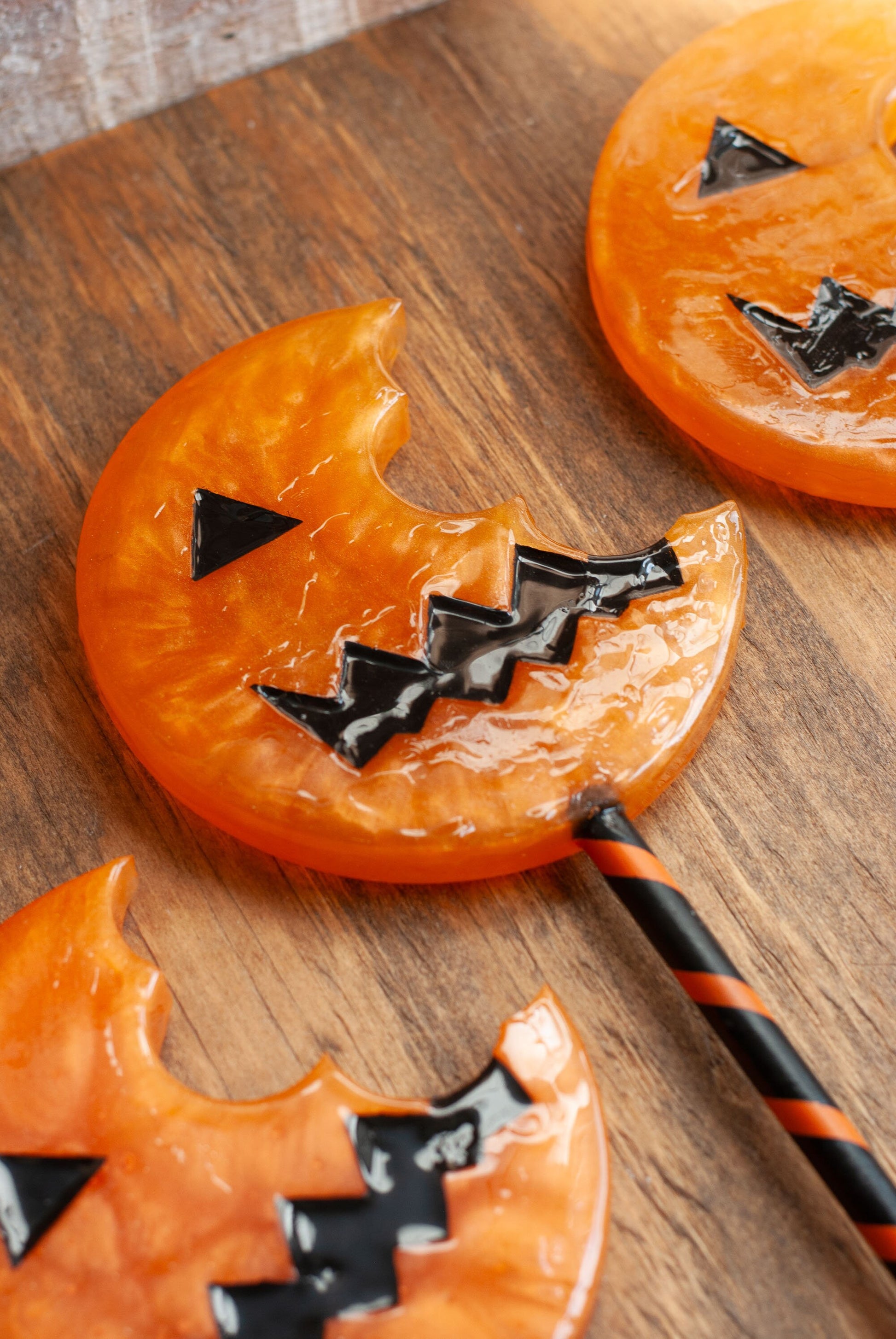 Close up of a black and orange Halloween-themed horror movie pumpkin lollipop prop made of resin for trick or treat and cosplay displayed on wooden table