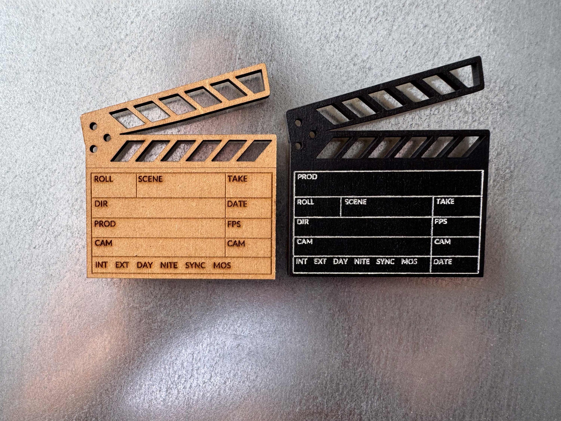 side by side view of two personalized engraved wooden clapboard magnets in brown and black on a metal refrigerator