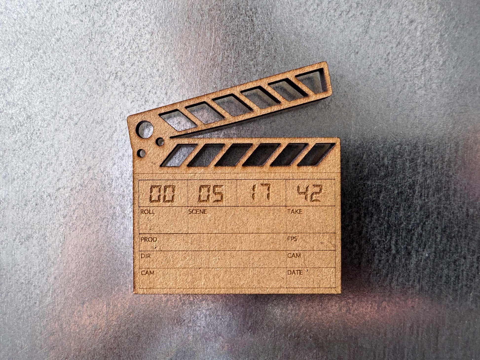 close up view of a brown wood clapboard magnet on a metal fridge with a custom laser engraved date