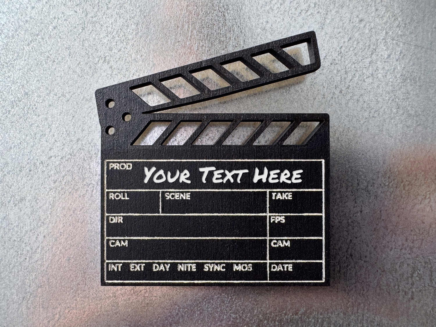 close up view of a black engraved wood clapboard magnet on a metal fridge with custom text