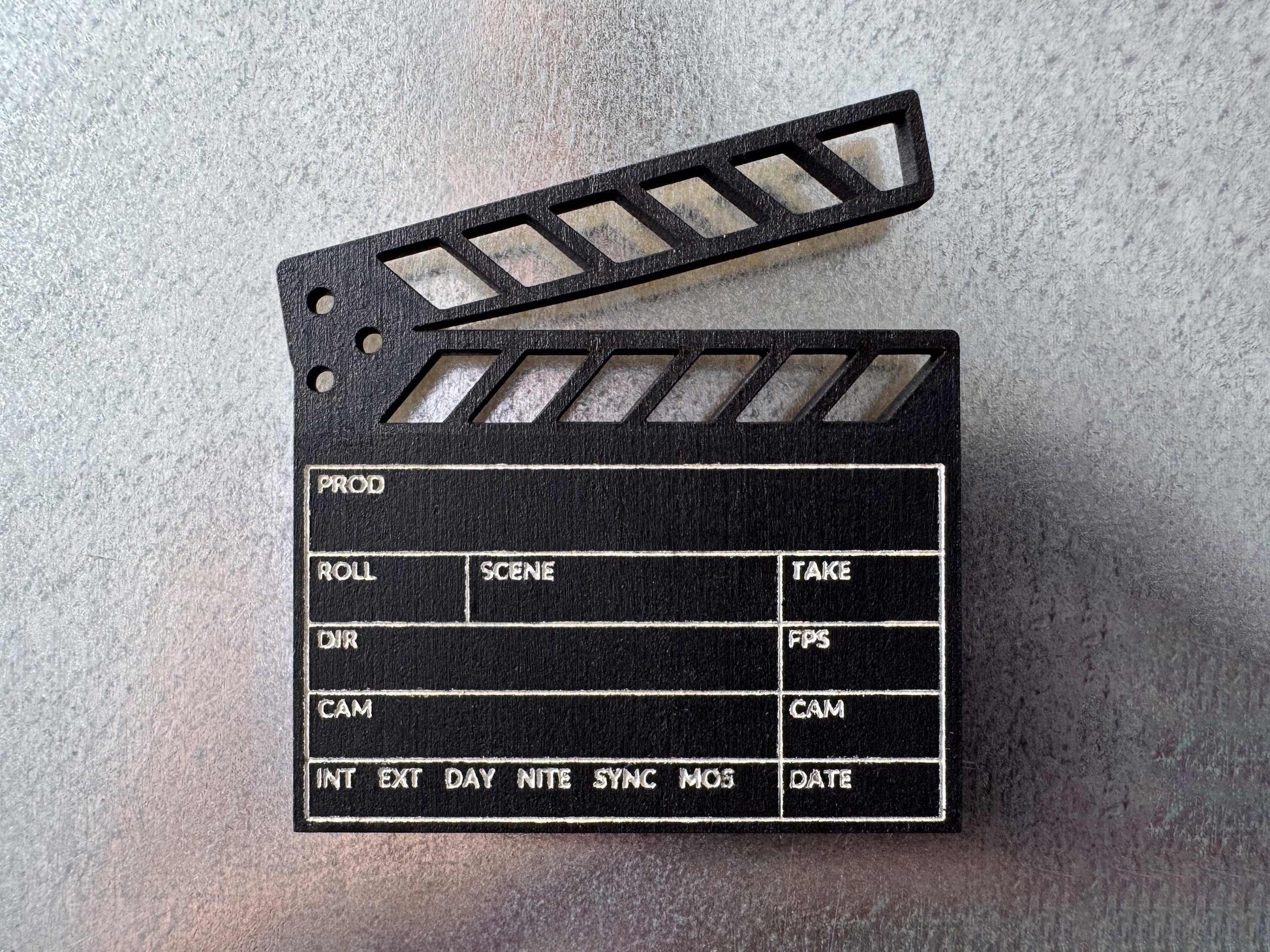 close up view of a black engraved wood clapboard magnet on a metal fridge