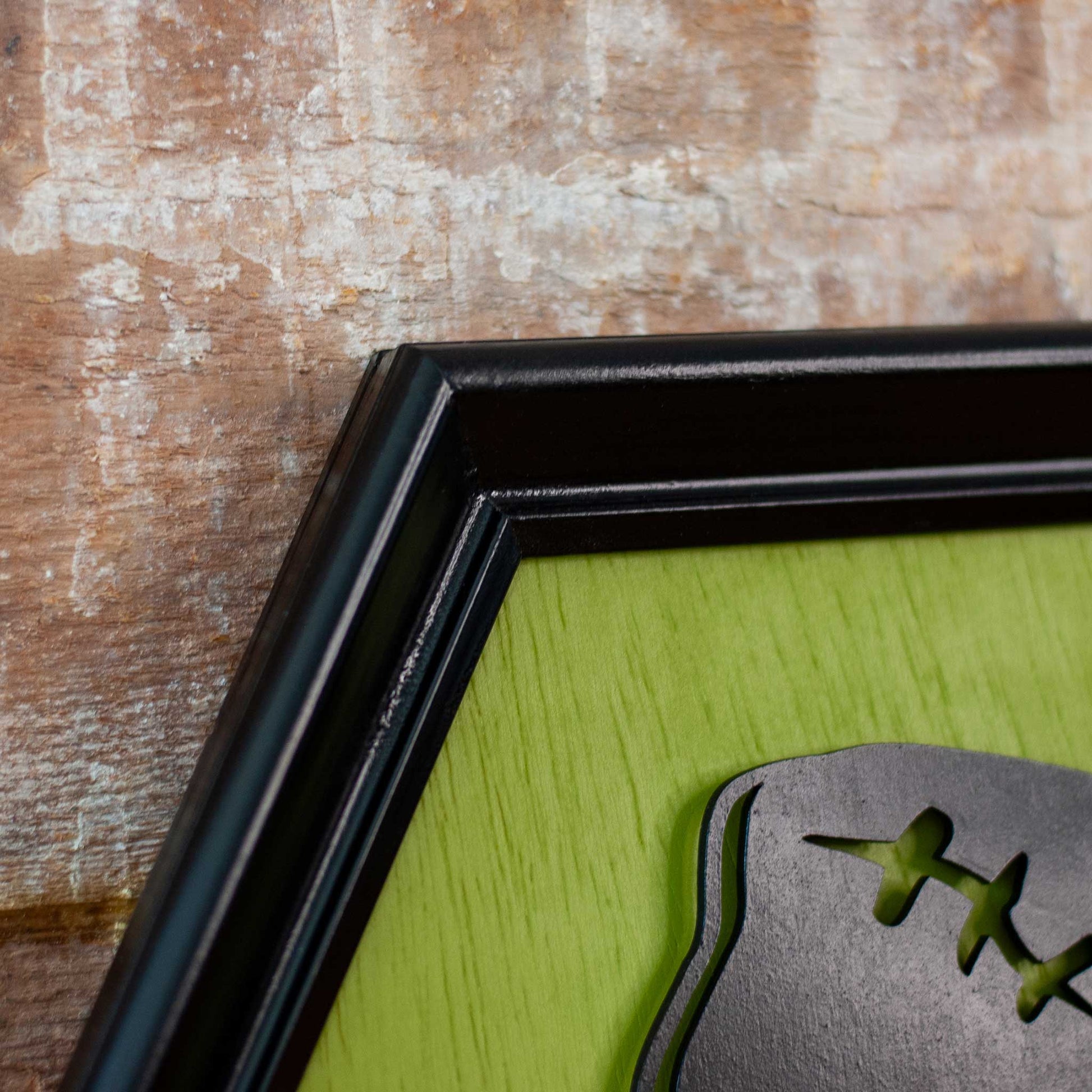 Close-up of a black framed picture with a green background and Frankenstein silhouette on a wooden surface