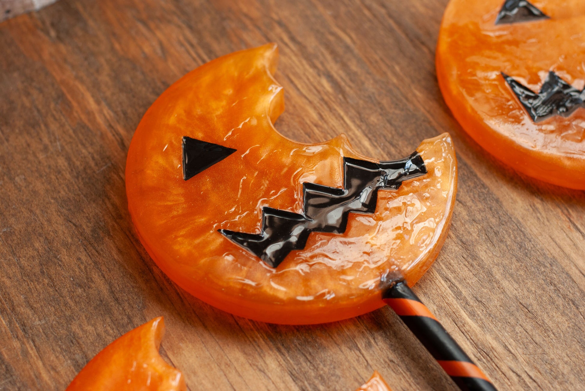 Black and orange Halloween-themed horror movie pumpkin lollipop props made of resin for trick or treat and cosplay displayed on wooden table