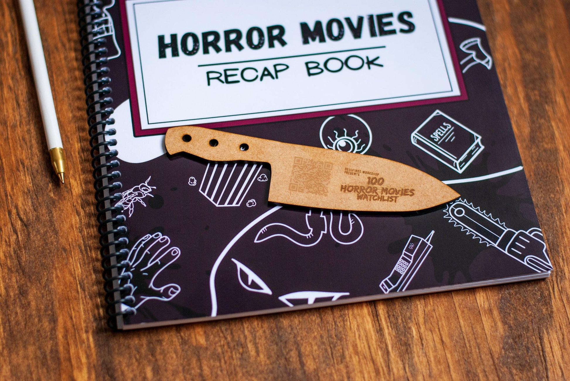 a close up view of Horror Movie Recap Book movie review journal and wooden bookmark with QR code watchlist