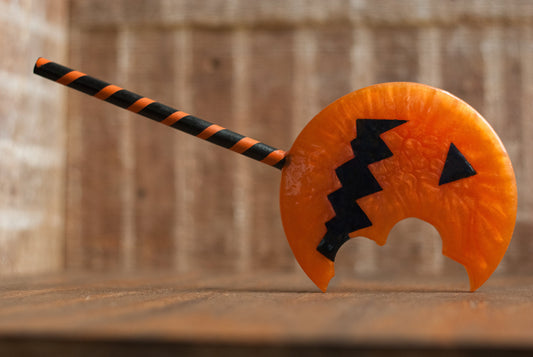 Black and orange Halloween-themed horror movie pumpkin lollipop prop made of resin for trick or treat and cosplay displayed on wooden table