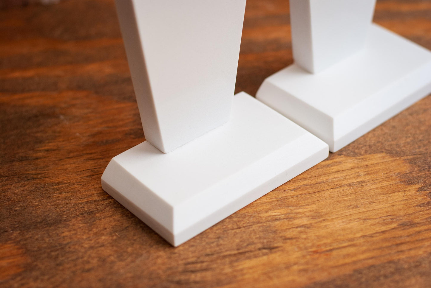 Detailed view of two decorative coffin-shaped bookends made of white marble on a wooden table with a textured wood background