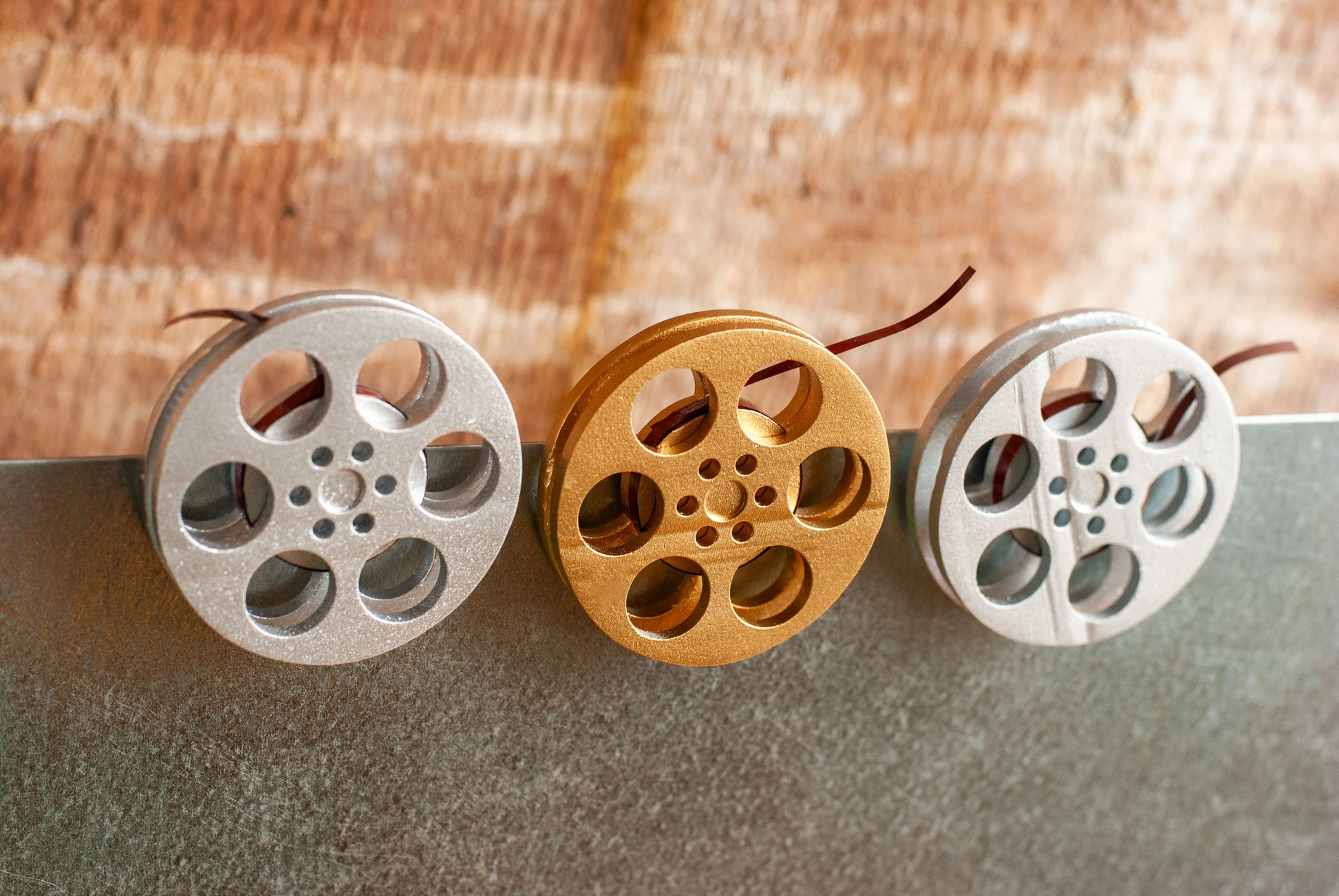 front view of a gold and silver miniature movie reel magnets hanging on fridge