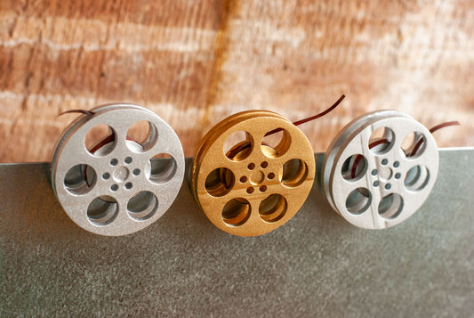 front view of a gold and silver miniature movie reel magnets hanging on fridge