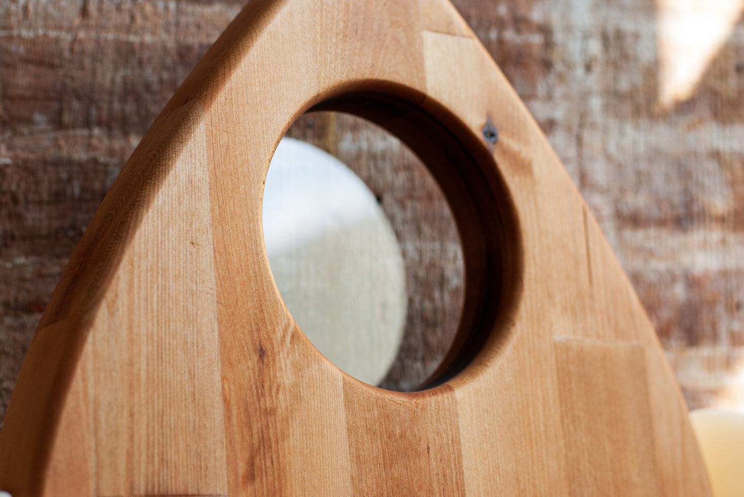 Wooden planchette-shaped charcuterie board with a clear circular looking hole on a blurred natural background