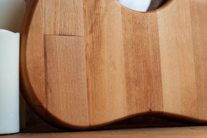 Close-up of a hickory wood planchette-shaped cutting board with a white candle beside it
