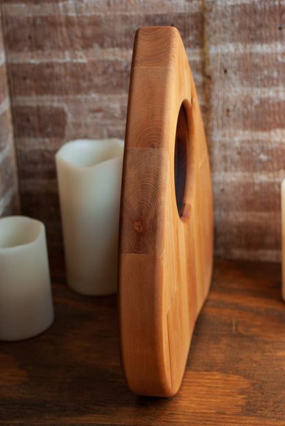 Side view of a wooden planchette-shaped cutting board with a rustic background