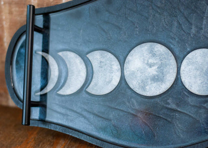 Decorative shimmery black wooden and resin tray with moon phases on a wooden surface