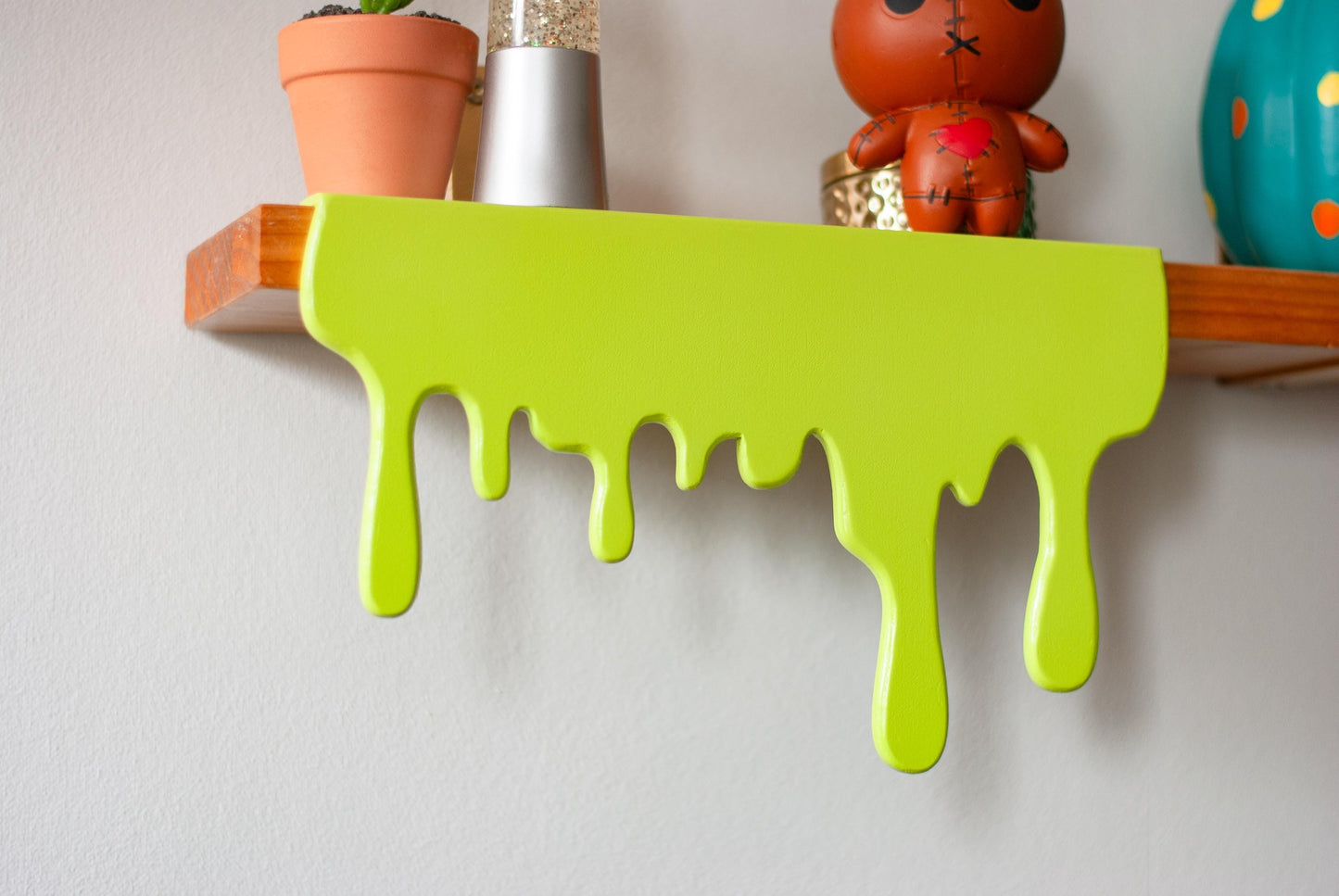 Front view of a green Slime Drip Shelf decor sitting on a wooden floating shelf, 90s Nostalgic shelf sitter, displaying Spooky Season vibes, an Accessory for Bookshelf, Display Shelf, or Mantel, Goosebumps inspired decor