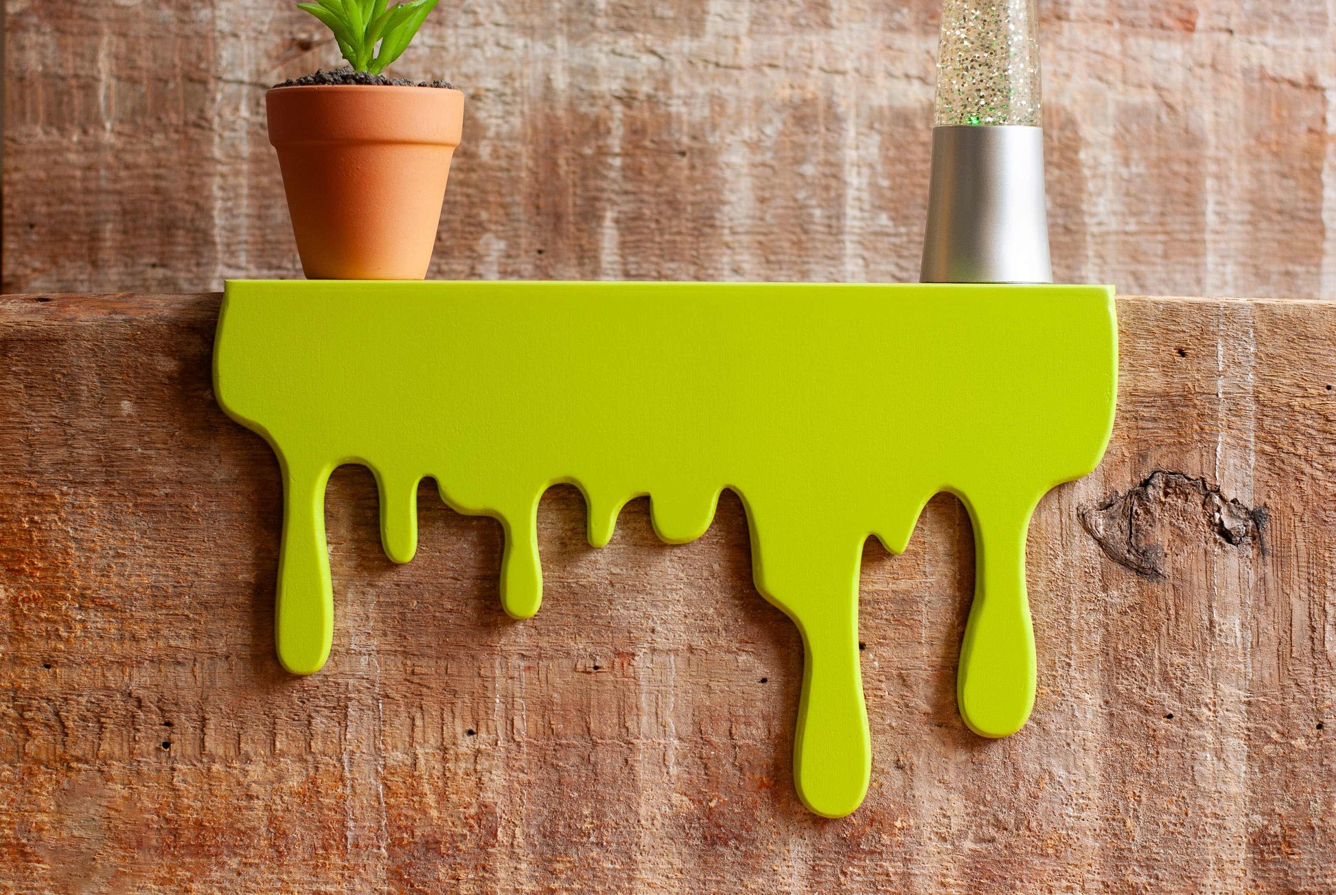 Front view of a floating green Slime Drip Shelf decor sitting on a wooden shelf, 90s Nostalgic shelf sitter, displaying Spooky Season vibes, an Accessory for Bookshelf, Display Shelf, or Mantel, Goosebumps inspired decor