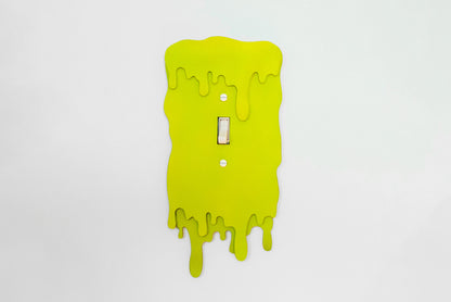 Green slime light switch cover with a dripping design on a white background