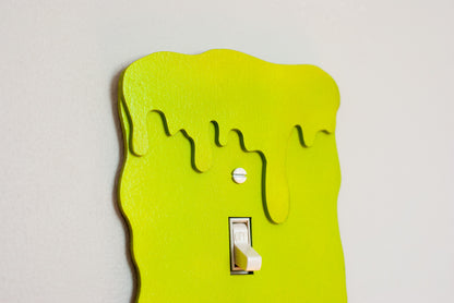 Close up of a green slime drip light switch cover with a unique design on a white background