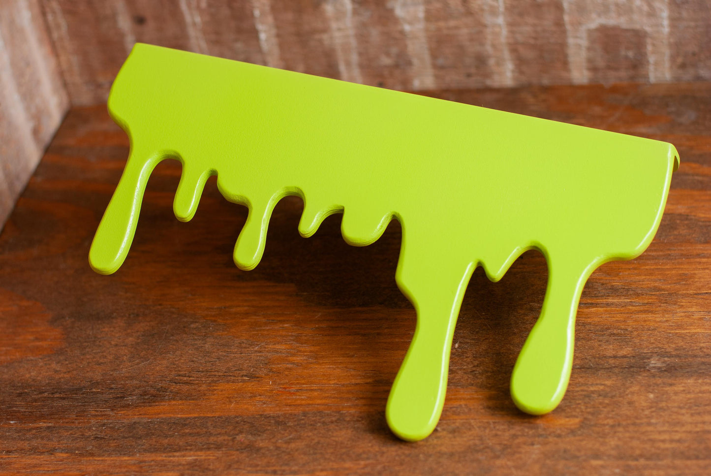 detailed view of a green Slime Drip Shelf decor sitting on a wooden table, 90s Nostalgic shelf sitter, displaying Spooky Season vibes, an Accessory for Bookshelf, Display Shelf, or Mantel, Goosebumps inspired decor