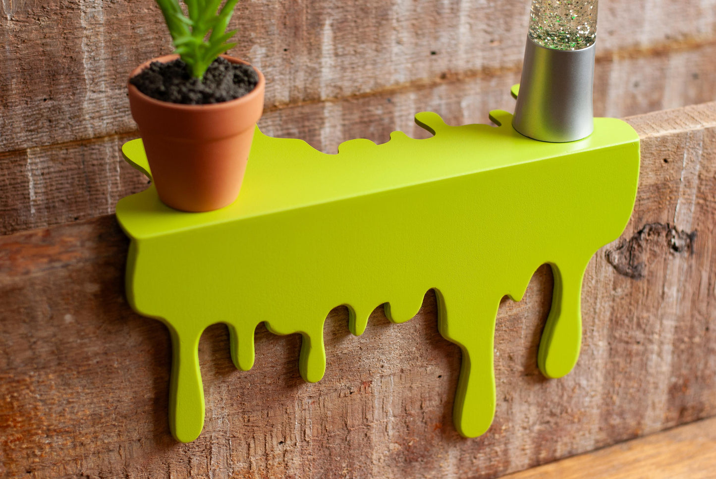 top view of a green Slime Drip Shelf decor sitting on a wooden floating shelf, 90s Nostalgic shelf sitter, displaying Spooky Season vibes, an Accessory for Bookshelf, Display Shelf, or Mantel, Goosebumps inspired decor