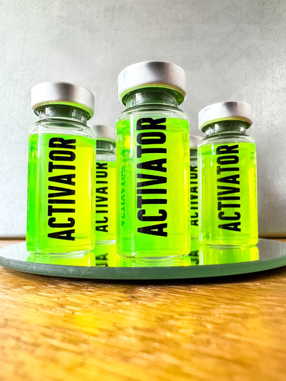 Four The Substance 'Activator' movie prop replica bottles with green liquid on a wooden surface