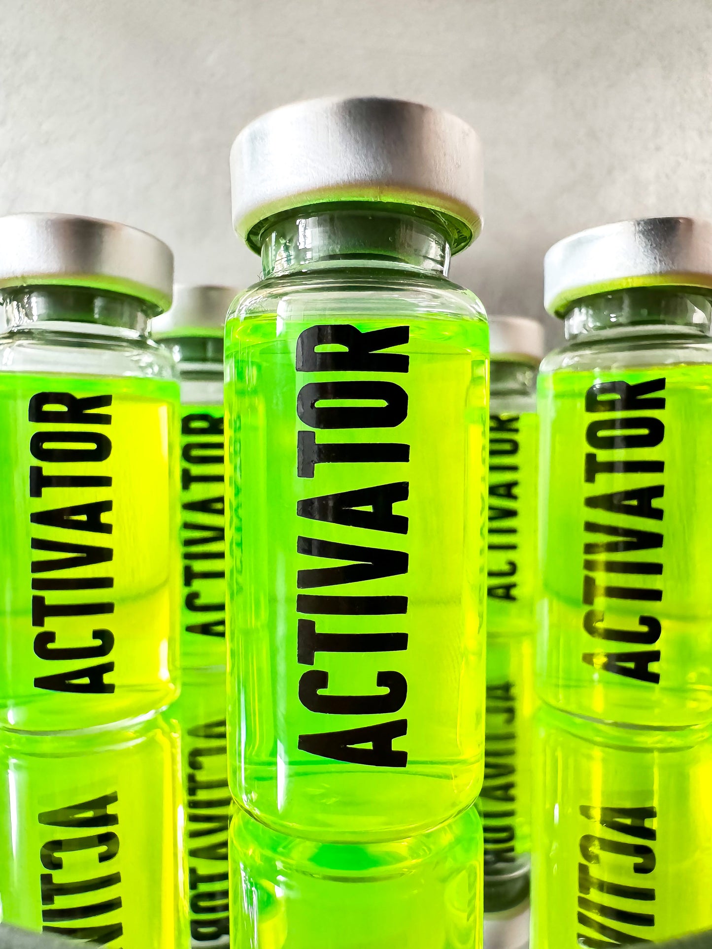 The Substance glass vial movie props labeled 'Activator' with a green liquid on a reflective surface.