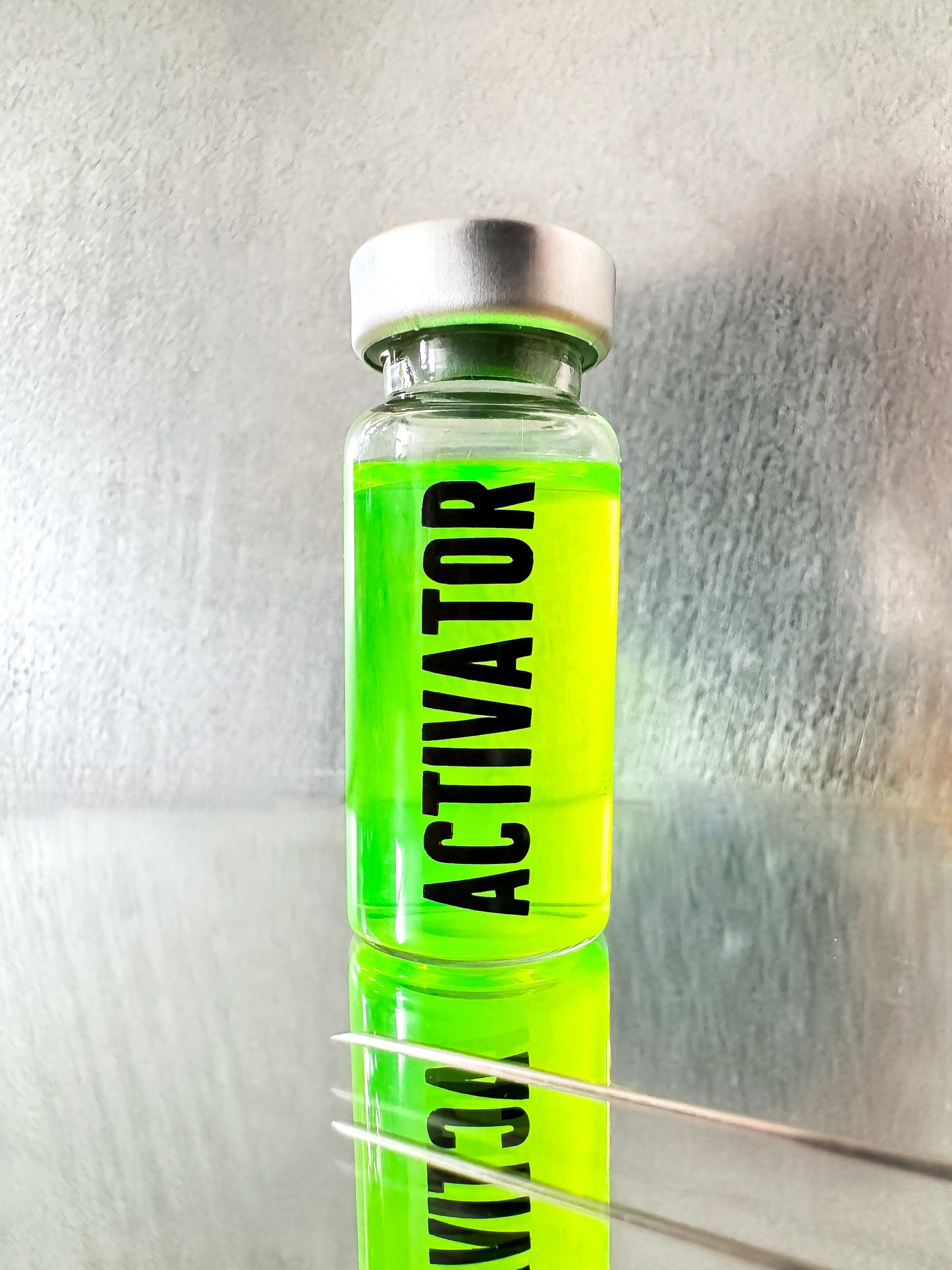 The Substance glass vial movie props labeled 'ACTIVATOR' with a green liquid and syringe on a metallic surface.
