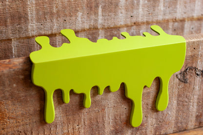 top view of a green Slime Drip Shelf decor sitting on a wooden floating shelf, 90s Nostalgic shelf sitter, displaying Spooky Season vibes, an Accessory for Bookshelf, Display Shelf, or Mantel, Goosebumps inspired decor