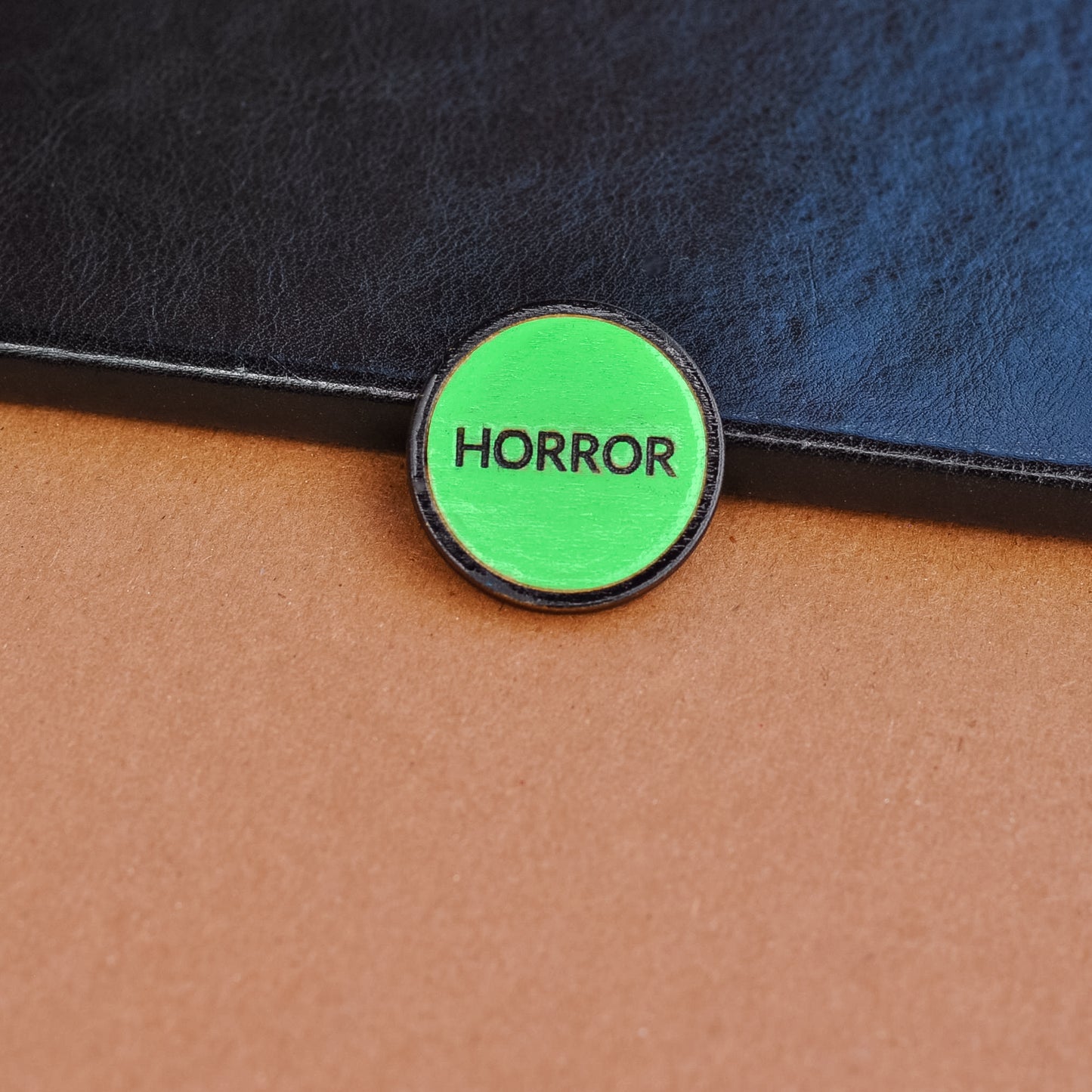 Green retro vhs label horror pinback style button that reads 'Horror' on a textured surface